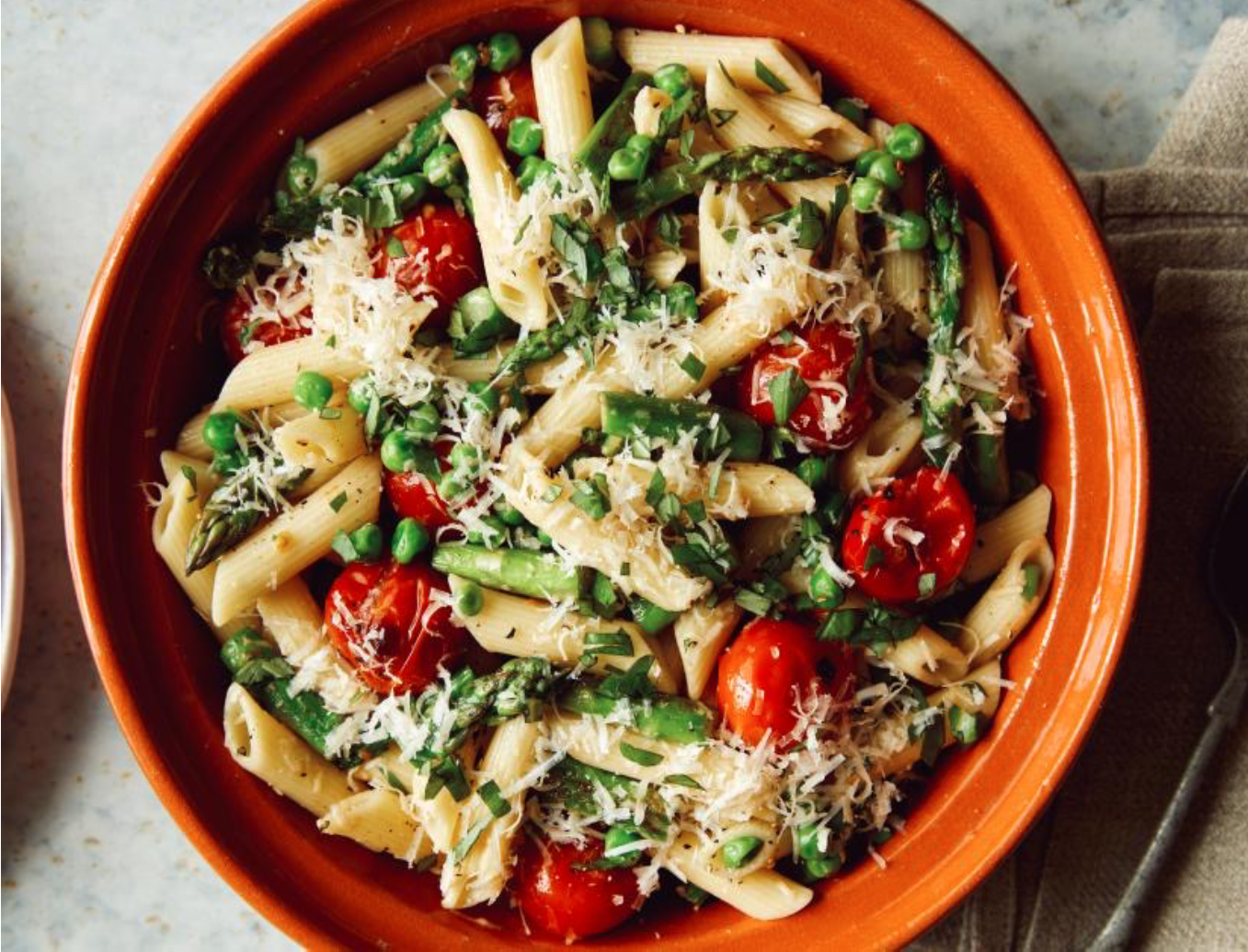 a bowl of pasta with peas, tomoatoes and asparagus